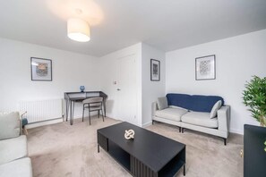 A modern living room with a sofa, a coffee table, a desk, and chairs. - The Gordon | Vacant Nests | Heart of Aberdeen (Aberdeen)