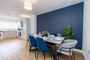 Ein moderner Essbereich mit dunkelblauer Akzentwand, einem Marmortisch und blauen StĂŒhlen.