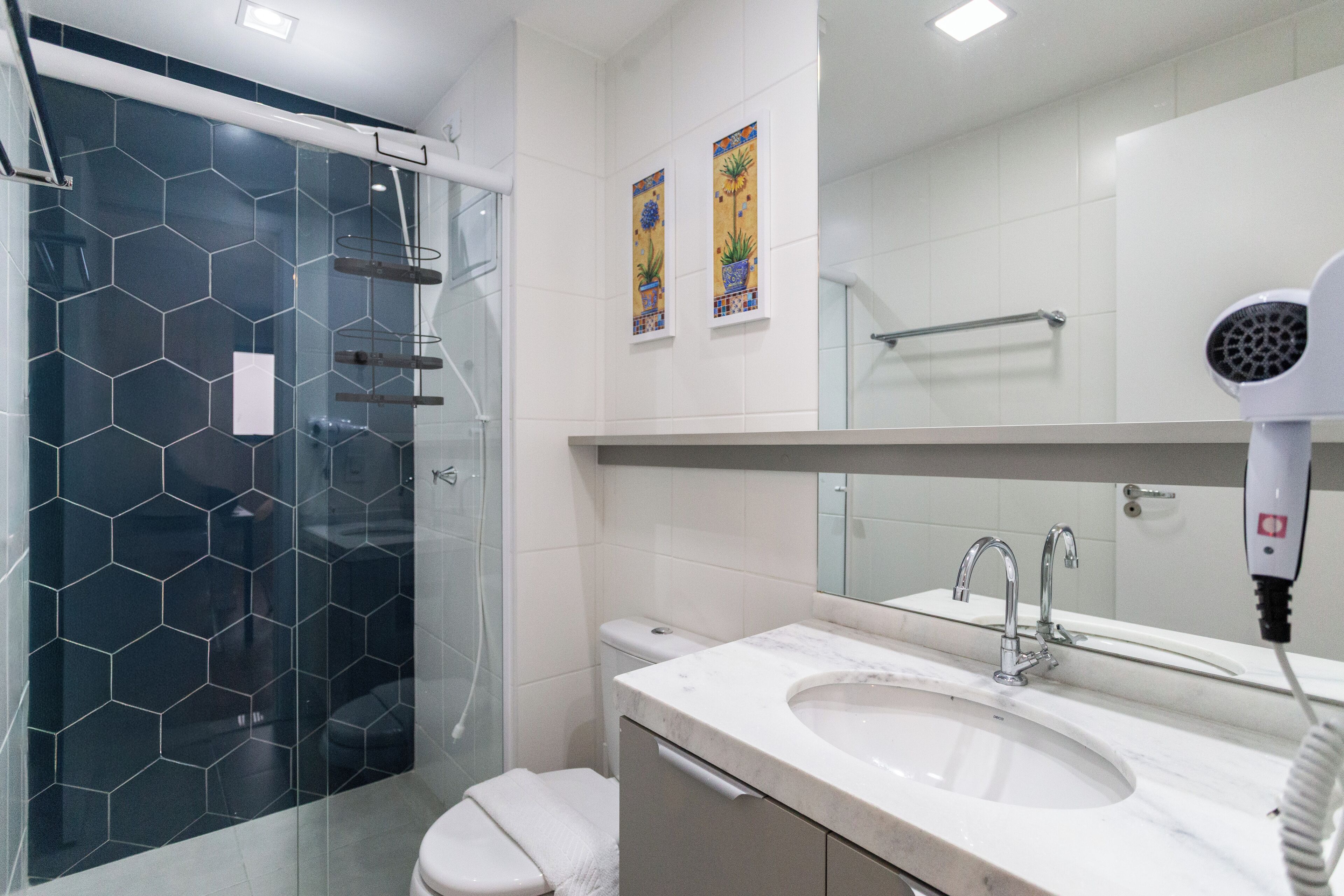 Une salle de bain moderne avec une douche à l’italienne en verre, un lavabo blanc et un grand miroir.