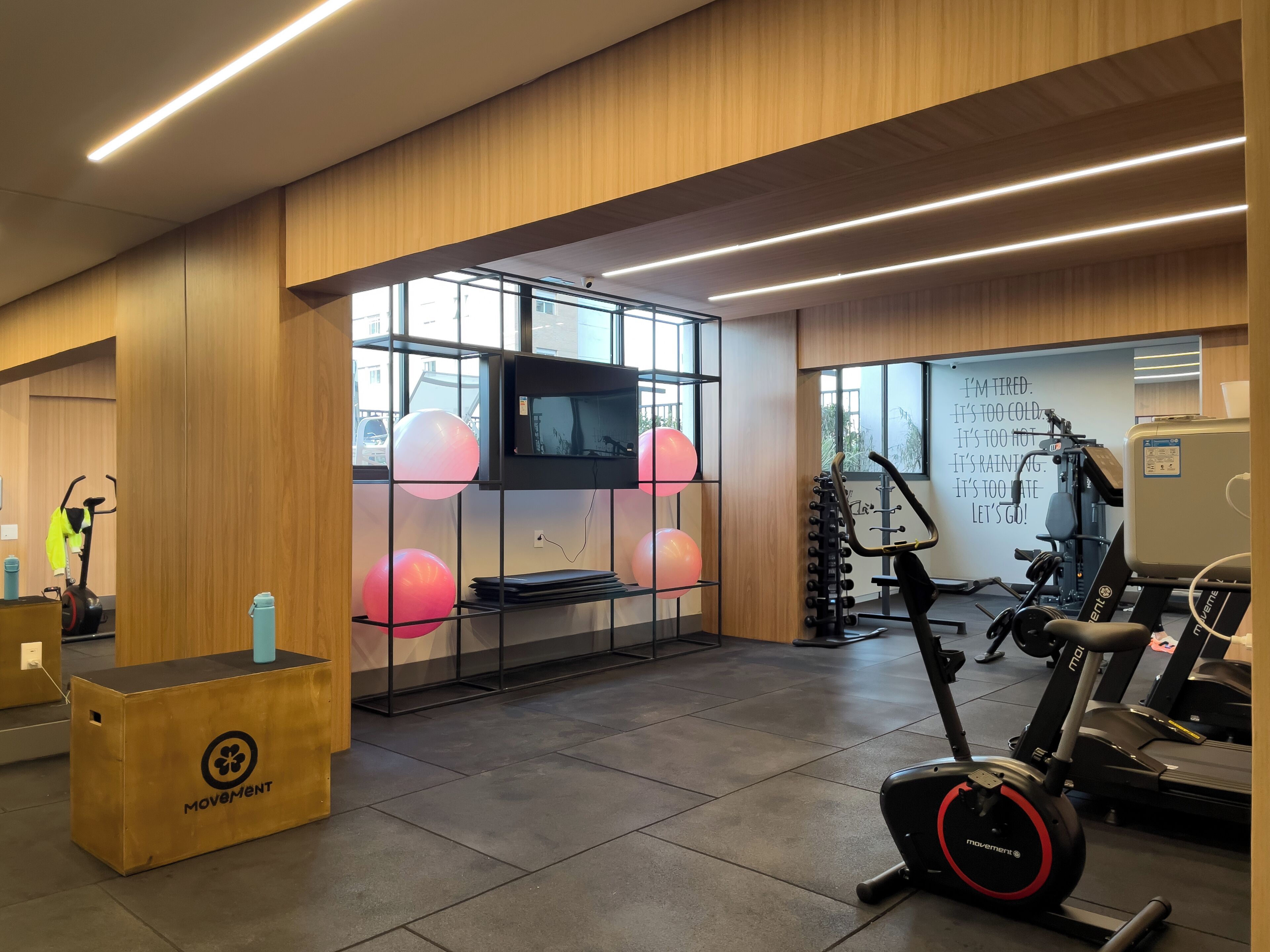 A gym with exercise equipment, a television on a wall, and a motivational quote.