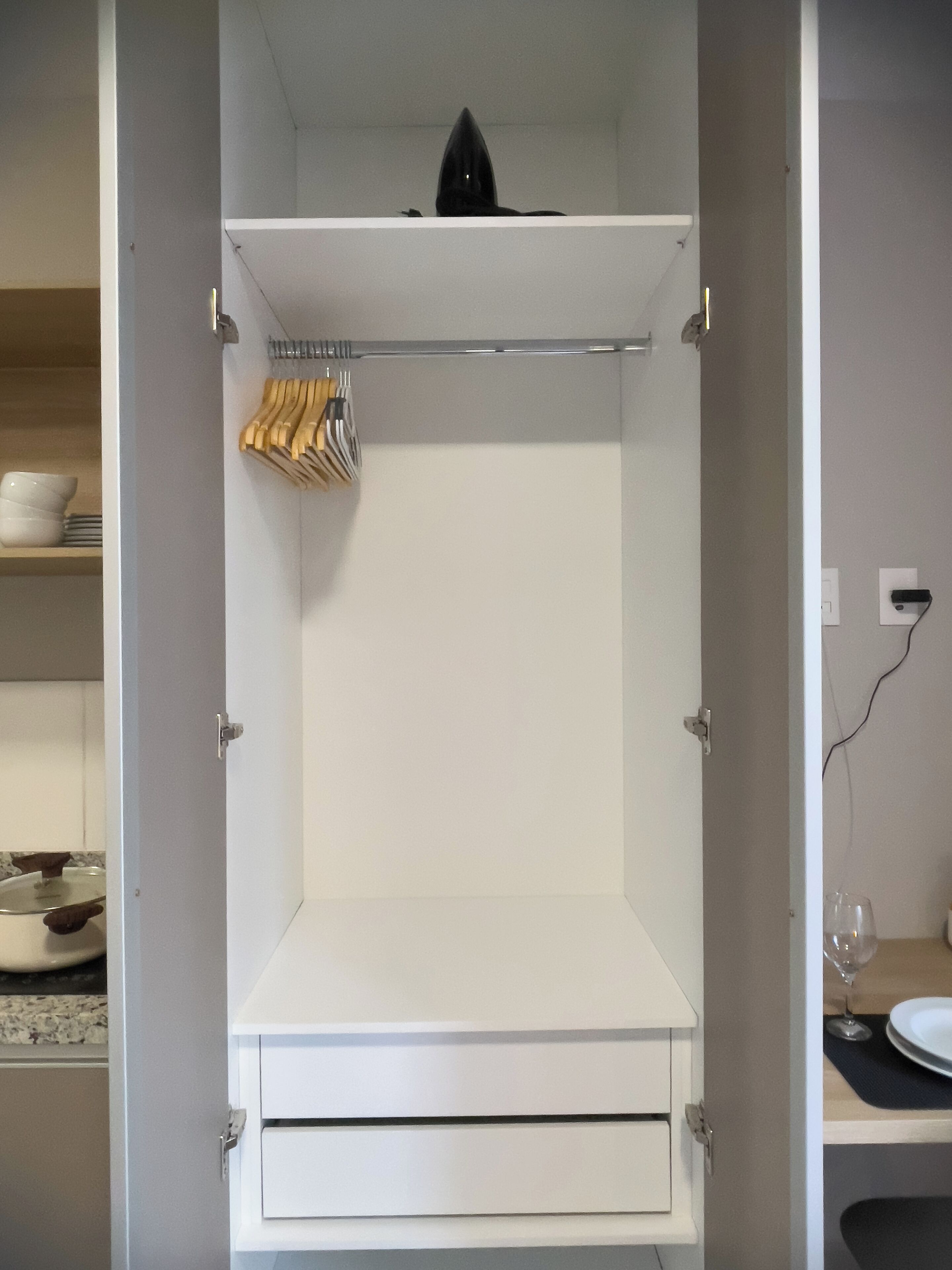 Un armario blanco con una barra para colgar y un cajón.