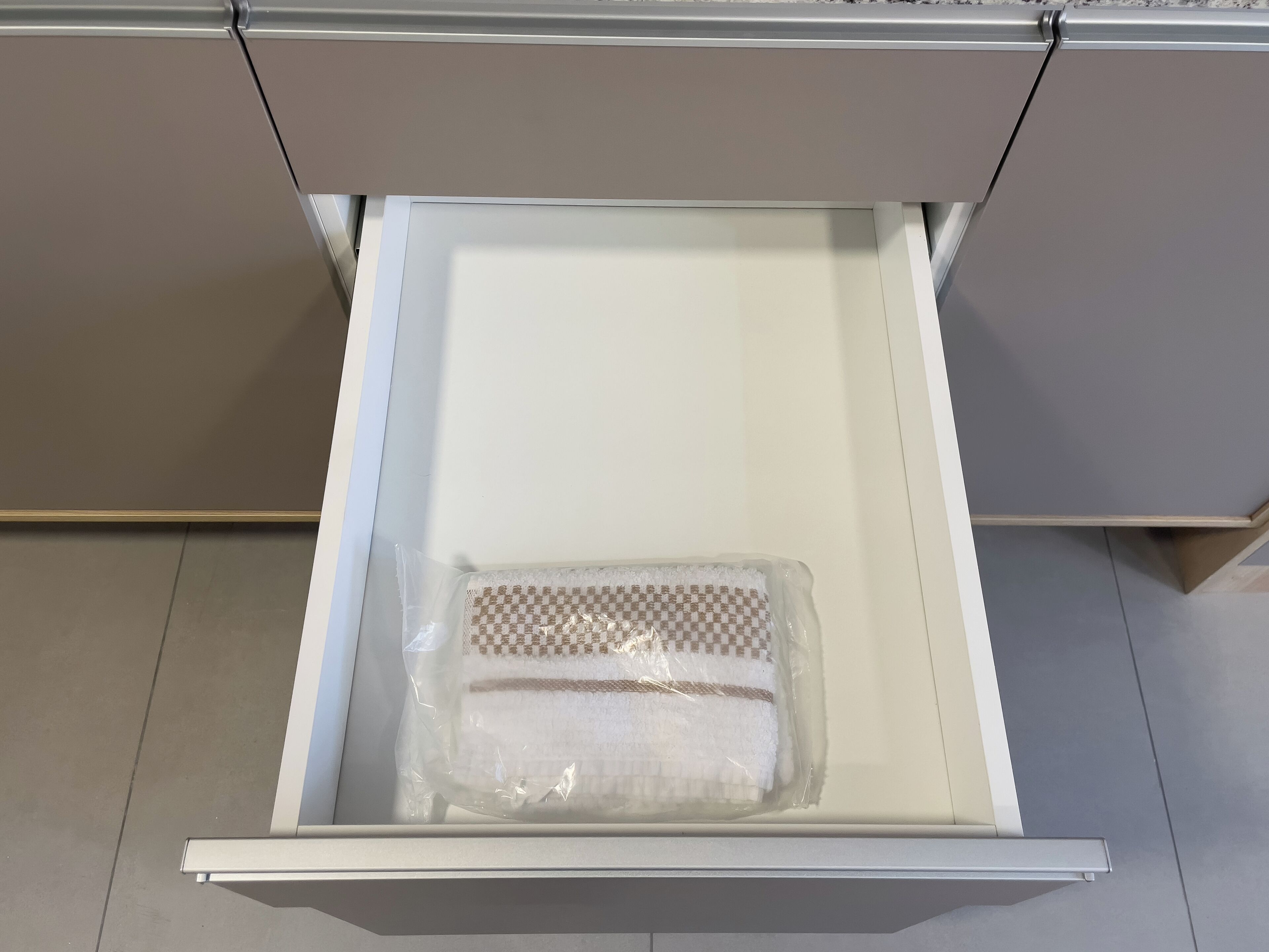A white drawer with a plastic-wrapped item inside.