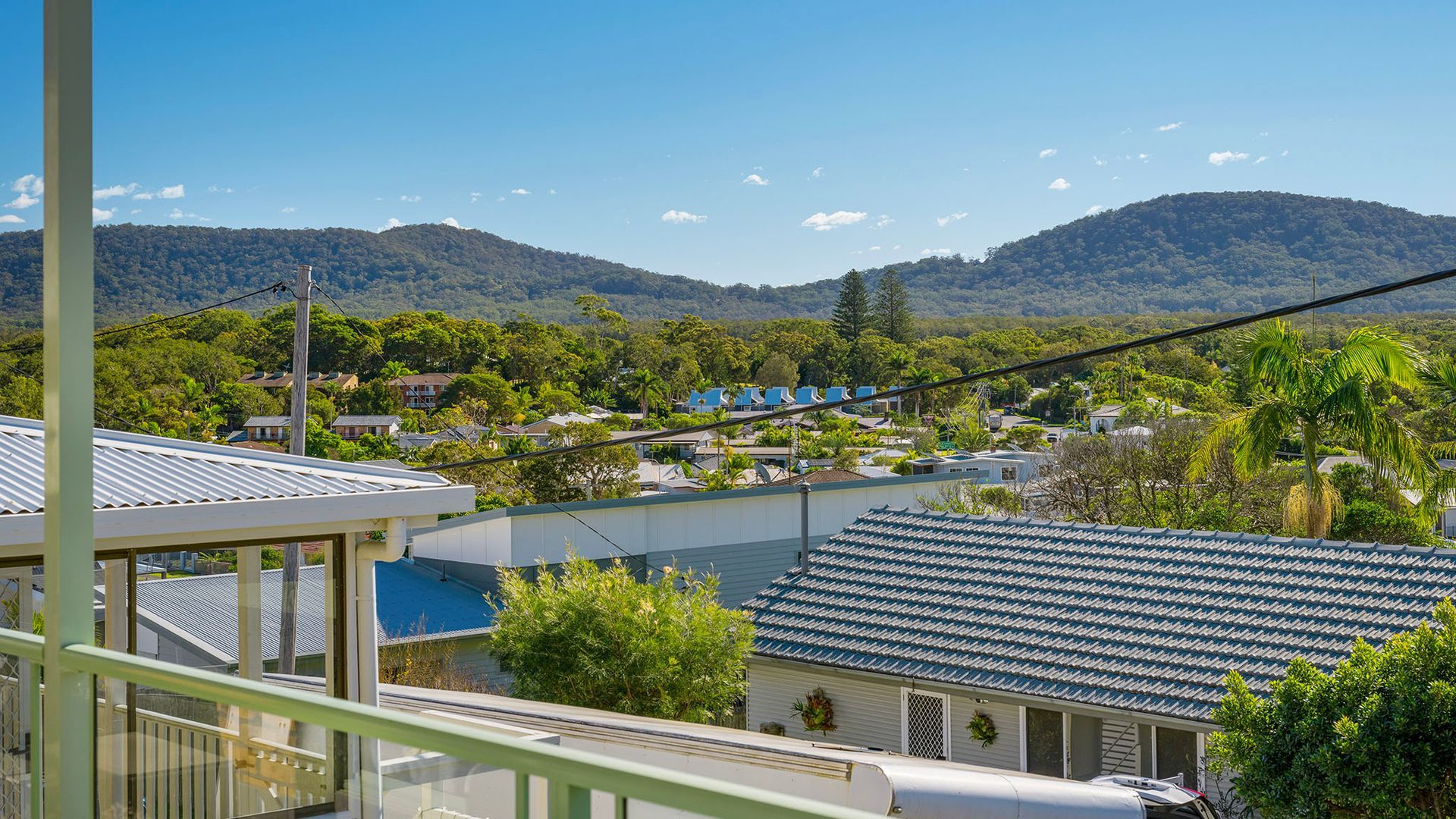 A residential area with houses, a clear sky, and mountains in the background.