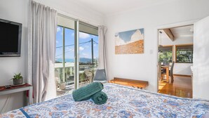 Ein Schlafzimmer mit einem Bett, einem Fernseher, einem Balkon mit Blick und einem Essbereich.