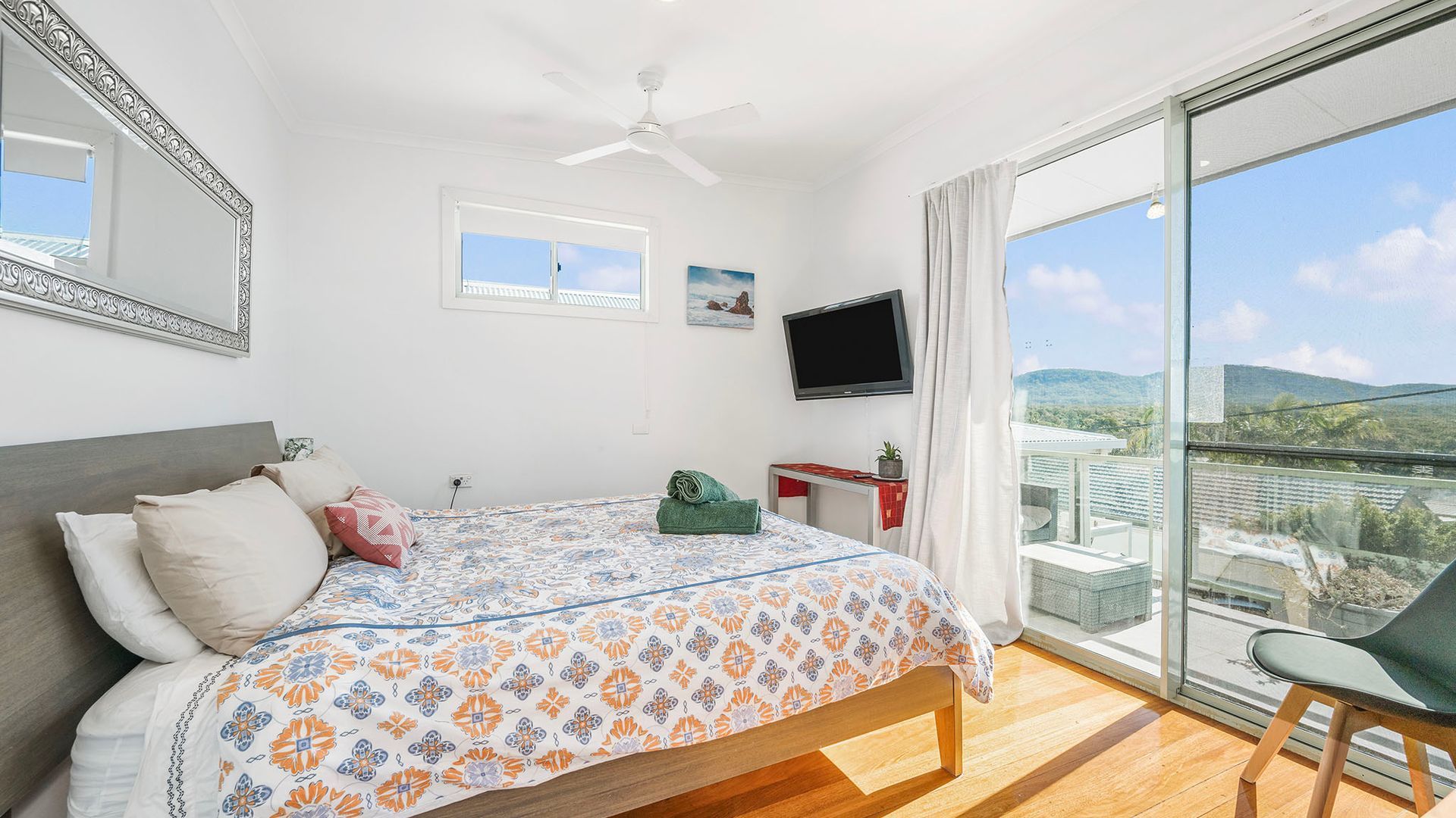 A bedroom with a bed, a TV, a desk, and a chair.