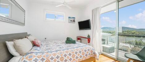 A bedroom with a bed, a TV, a desk, and a chair.
