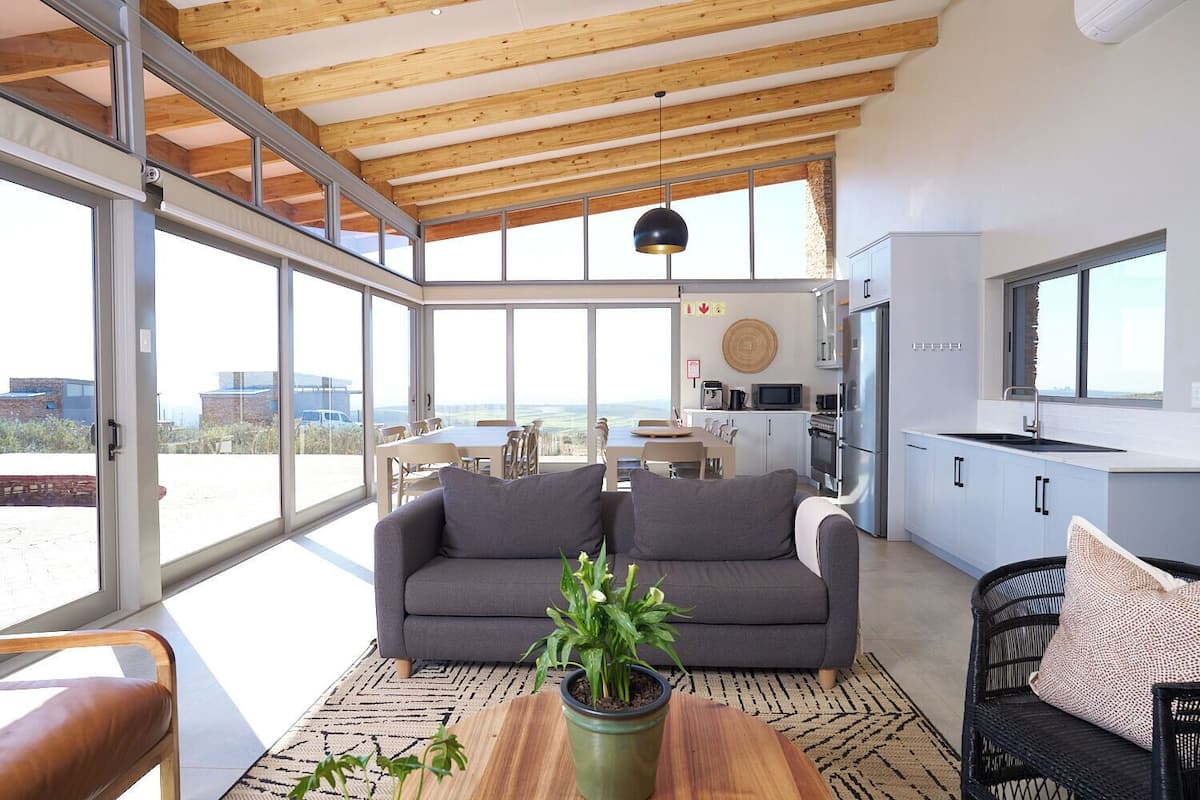 Un salón amplio con un sofá gris, una mesa de centro de madera y una planta en maceta.