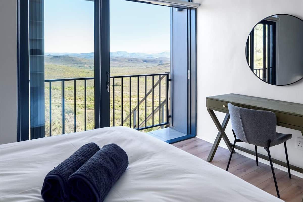 Habitación de hotel moderna con una cama grande, un escritorio y vistas al campo.