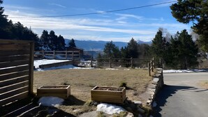 En lantlig fastighet med ett trästaket, en liten trähusliknande byggnad och utsikt över snöklädda berg.