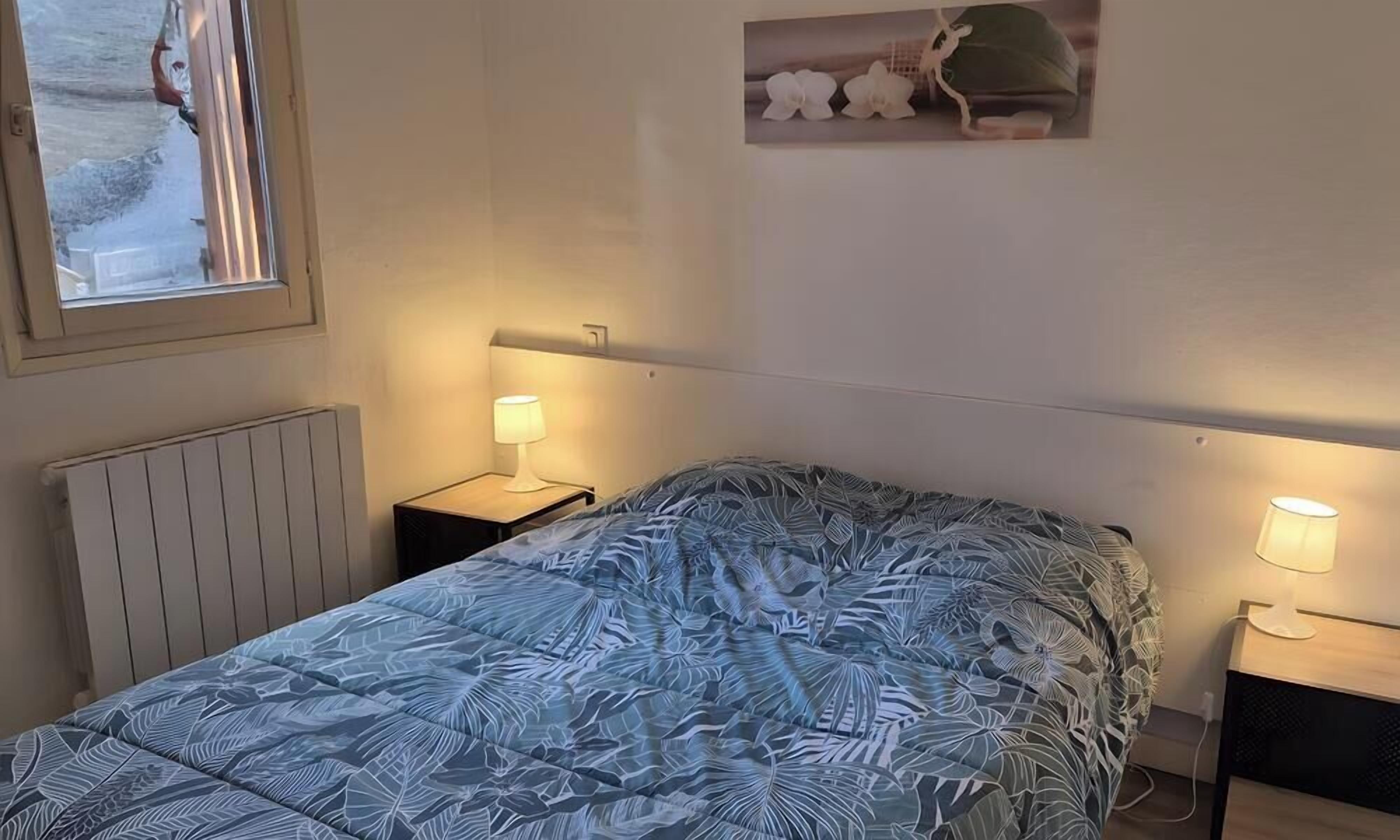 Une chambre à coucher avec un lit, une table de chevet avec une lampe, un radiateur et une fenêtre donnant sur un beau paysage.