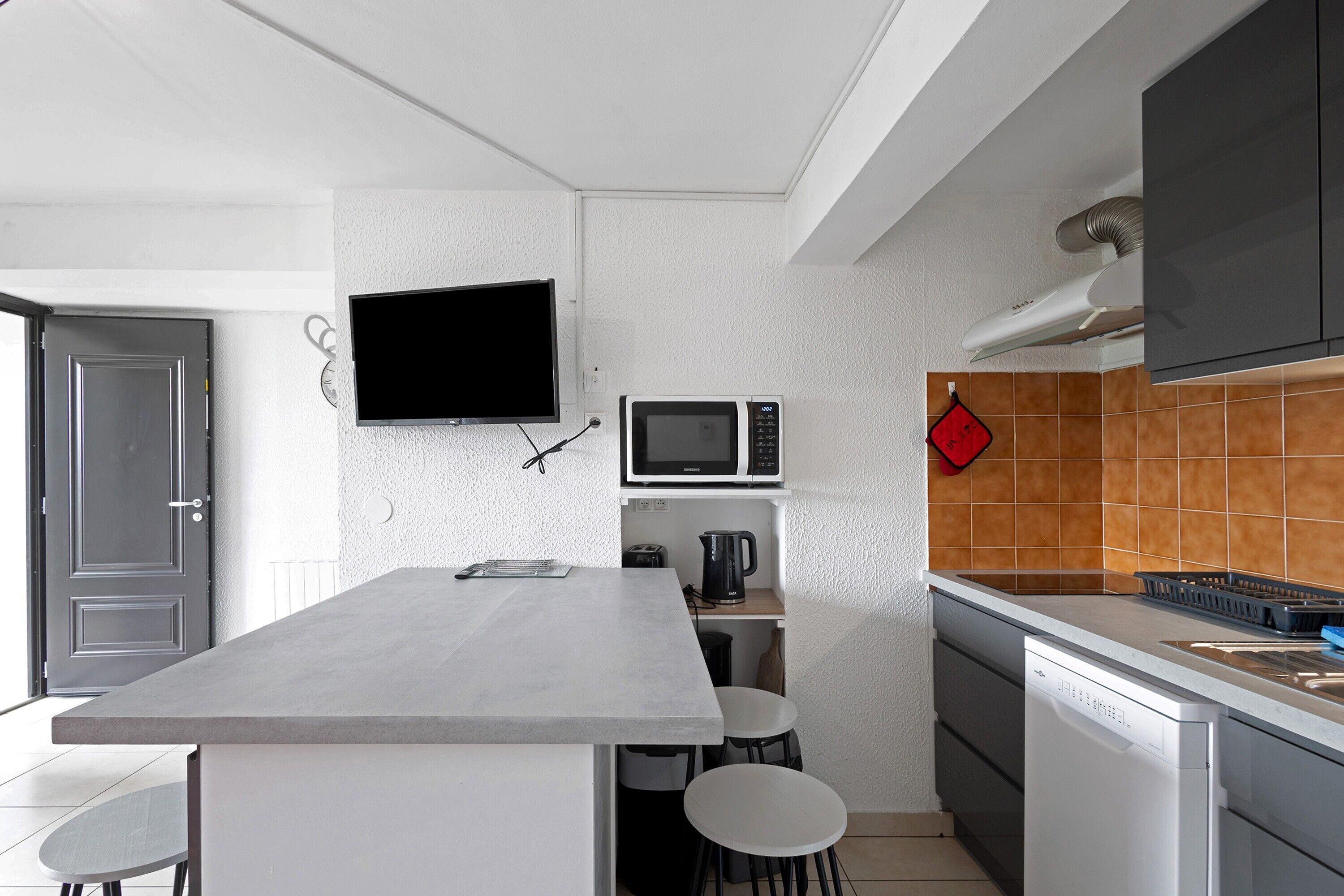 A modern kitchen with a flat-screen TV, microwave, and coffee maker.