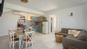 Una cocina moderna con armarios color turquesa, un refrigerador blanco y un comedor con mesa de madera y sillas blancas.