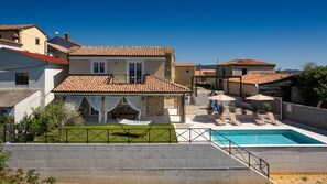 Une villa dotée d’une piscine, d’un espace extérieur aménagé et d’une terrasse couverte.