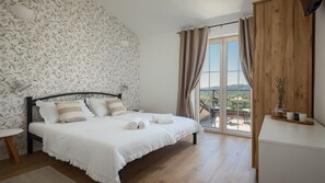 Une chambre à coucher avec un lit, une table de chevet, une fenêtre avec des rideaux et une vue sur l’extérieur.