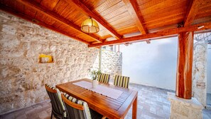 Une table en bois avec des chaises, un mur en pierre et une structure de plafond en bois.