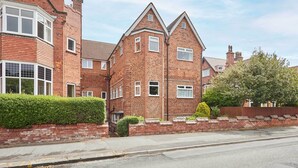 A two-story brick house with a prominent bay window on the left and a triangular gable on the right. - Host & Stay | LOOK Flat (Scarborough)