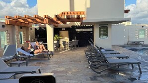 A poolside area with lounge chairs, a no-glass policy sign, and a stone-tiled floor. - Stay steps from the sand in this private studio at the Imperial Resort. Walk to shops, dining & nightlife. Rooftop pool, hot tub, gym, and kitchen included! (Honolulu)