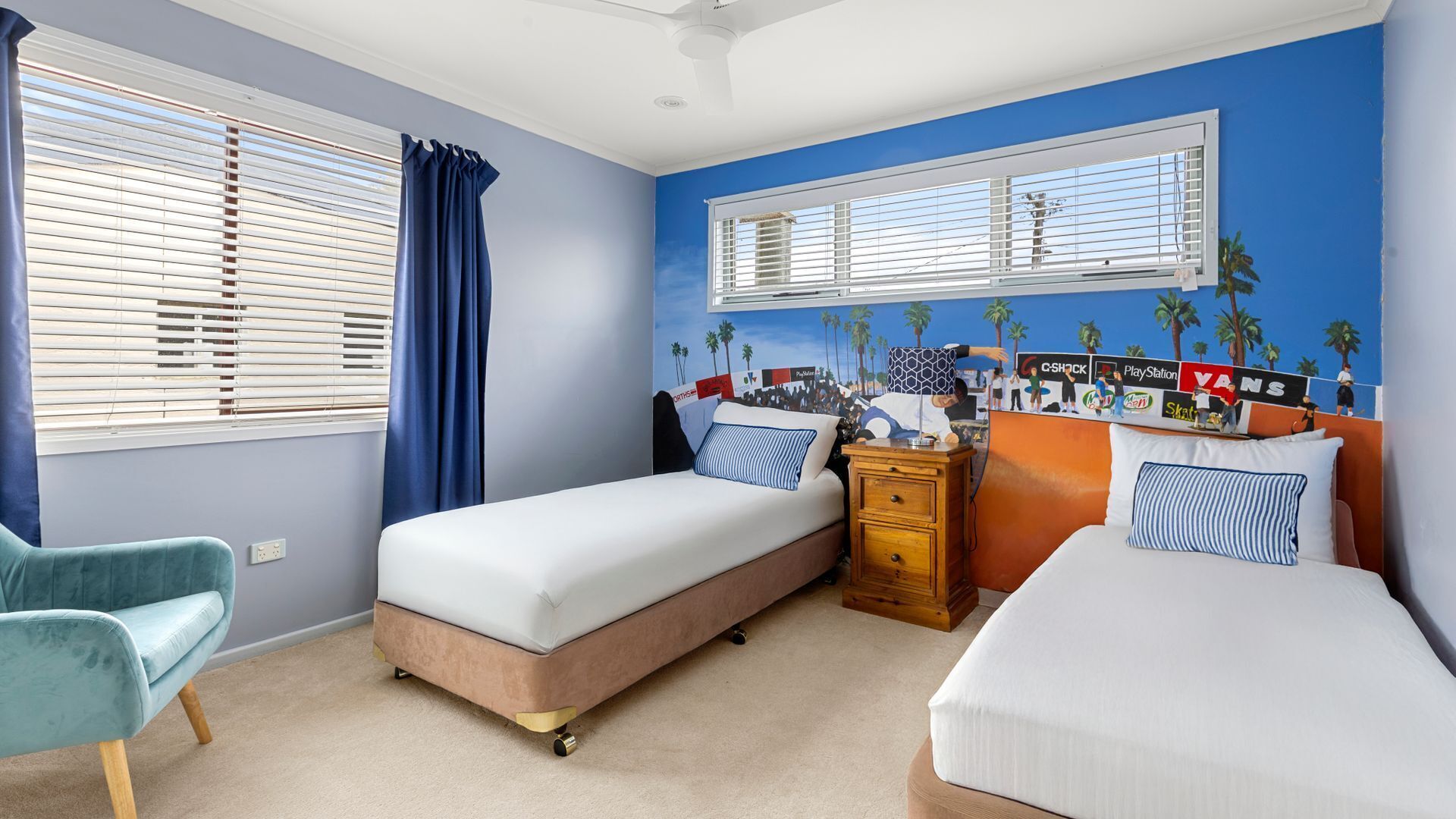 A bedroom with two beds, a dresser, a chair, and a window with blinds.