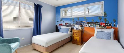 A bedroom with two beds, a dresser, a chair, and a window with blinds.
