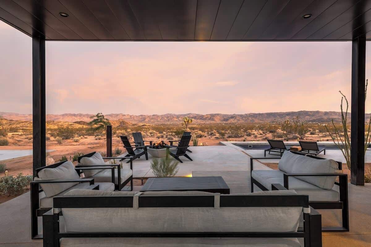 Un espace extérieur aménagé avec des meubles modernes et offrant une vue sur un paysage désertique.
