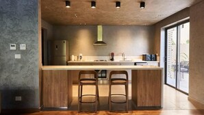 Una cucina moderna con isola centrale, due sgabelli da bar e una grande finestra che offre vista all'esterno.