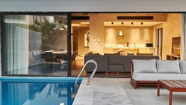 Un soggiorno moderno con piscina, divano e tavolo da pranzo.