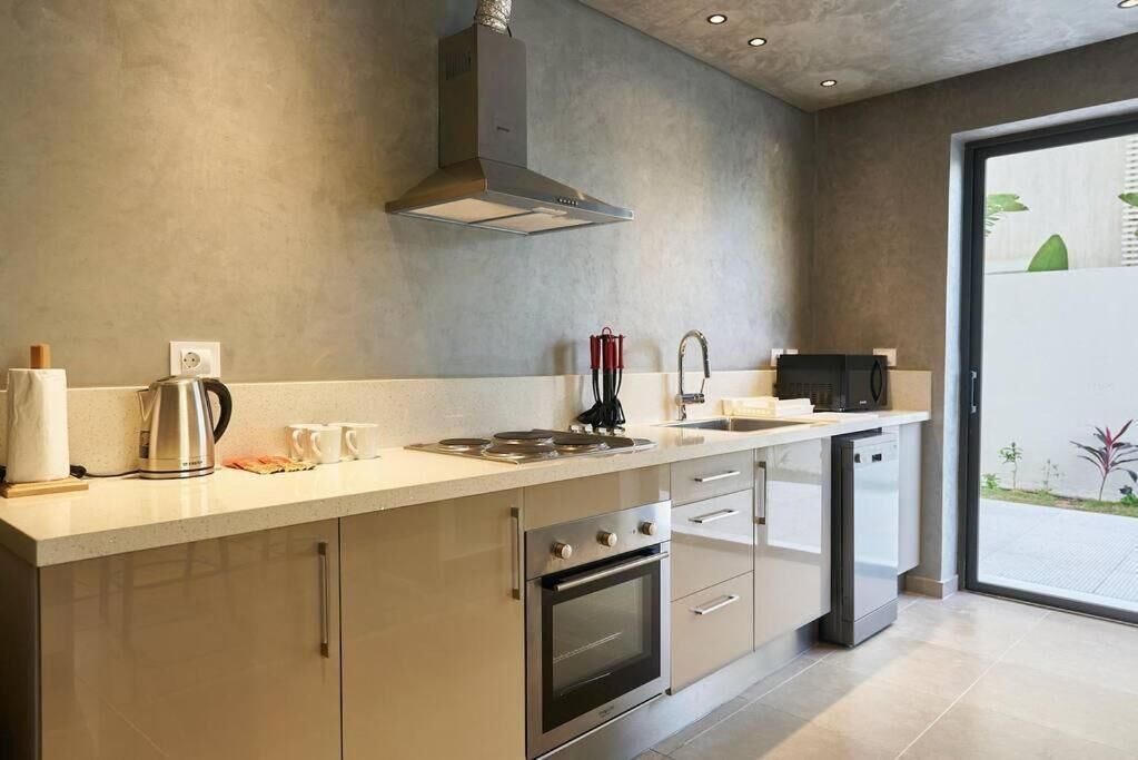 Una cocina moderna con una campana de acero inoxidable, un horno empotrado y un lavavajillas.