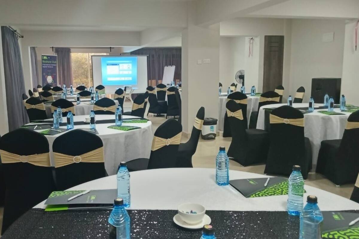 A conference room with multiple round tables, each with water bottles and notebooks.