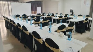 A conference room with multiple tables and chairs, each with water bottles and papers. - Downtown ecopark hotel (Kitui)
