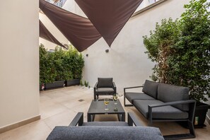 A patio with a table, two chairs, a sofa, and a potted plant.
