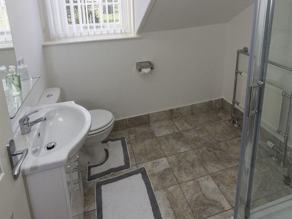 Un baño con lavamanos blanco, inodoro y zona de ducha.