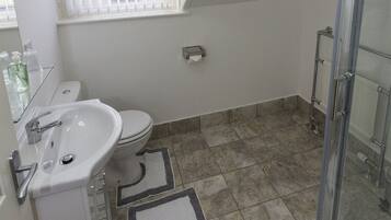 Un baño con lavamanos blanco, inodoro y zona de ducha.
