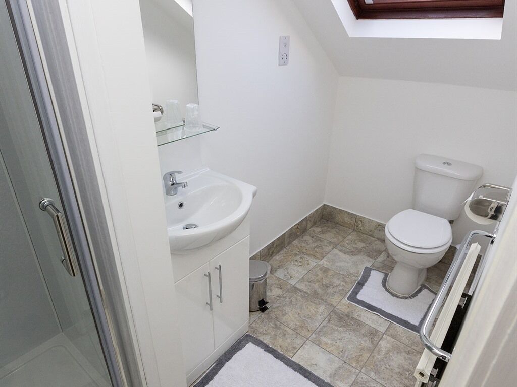 A compact bathroom with a white sink, toilet, and shower area.