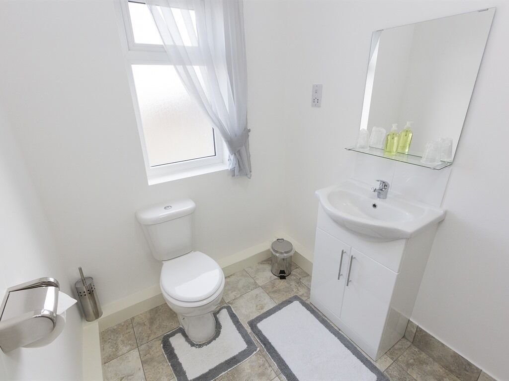 Een badkamer met toilet, wastafel en spiegel.