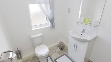 Een badkamer met toilet, wastafel en spiegel.