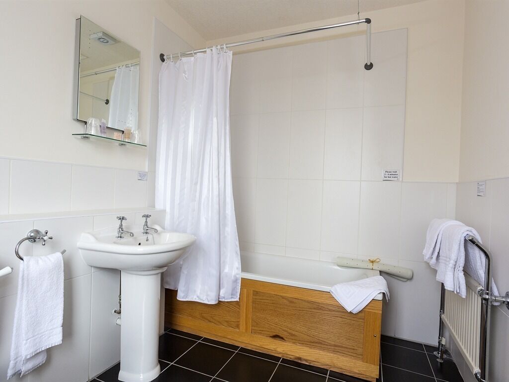 Een badkamer met een wit wastafel, spiegel en douchegordijn.