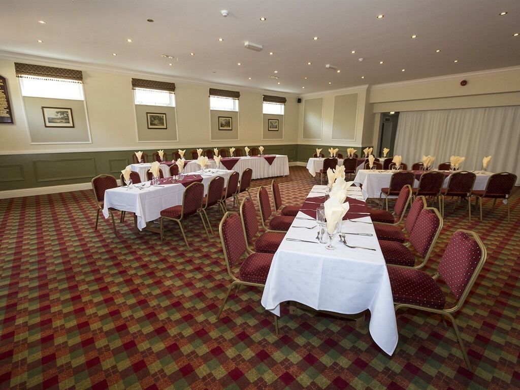 A conference room with multiple tables and chairs, arranged in rows.