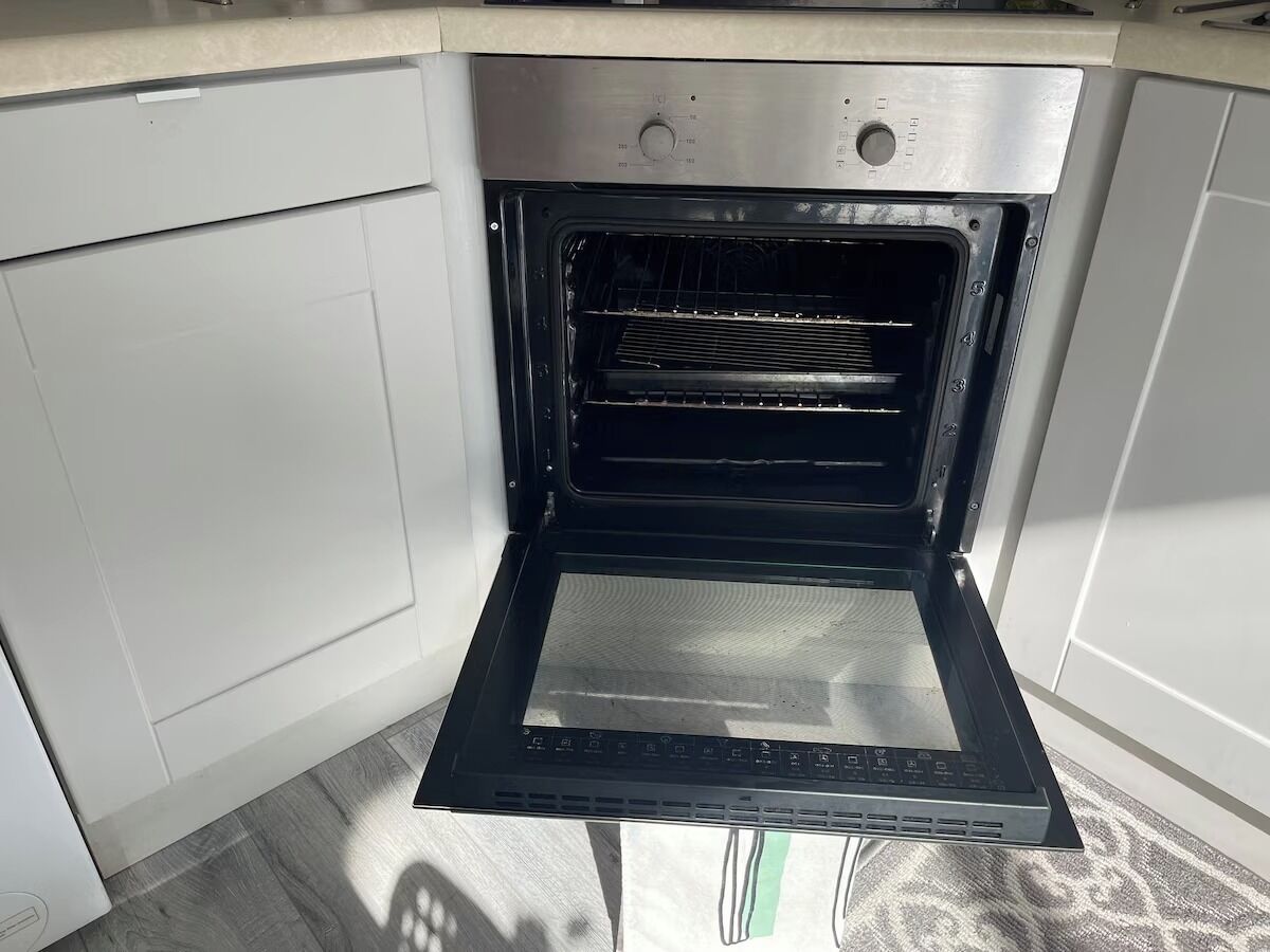 An open oven with a control panel and a glass door.