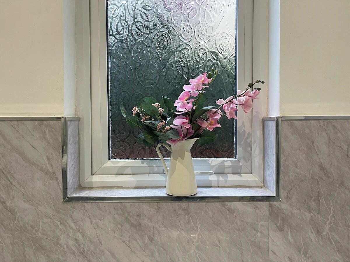 A vase with pink flowers on a windowsill.