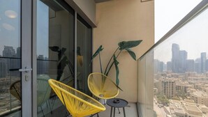 A balcony with two yellow chairs, a small table, and a view of a cityscape. - Lux 2BR Downtown Enjoy Full Burj Khalifa View (Dubai)