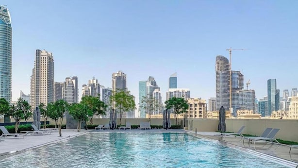 A swimming pool with lounge chairs and a city skyline in the background. - Lux 2BR Downtown Enjoy Full Burj Khalifa View (Dubai)