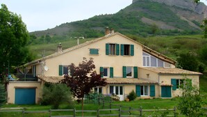 A two-story house with a tiled roof, a garage, and a fenced yard. - Farm Cottage "La Grange" (Garde-Colombe)
