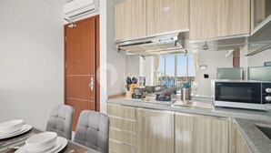 A modern kitchen with wooden cabinets, a built-in microwave, and a gas stove. - Maruva by Kozystay - Taman Sari (Jakarta)