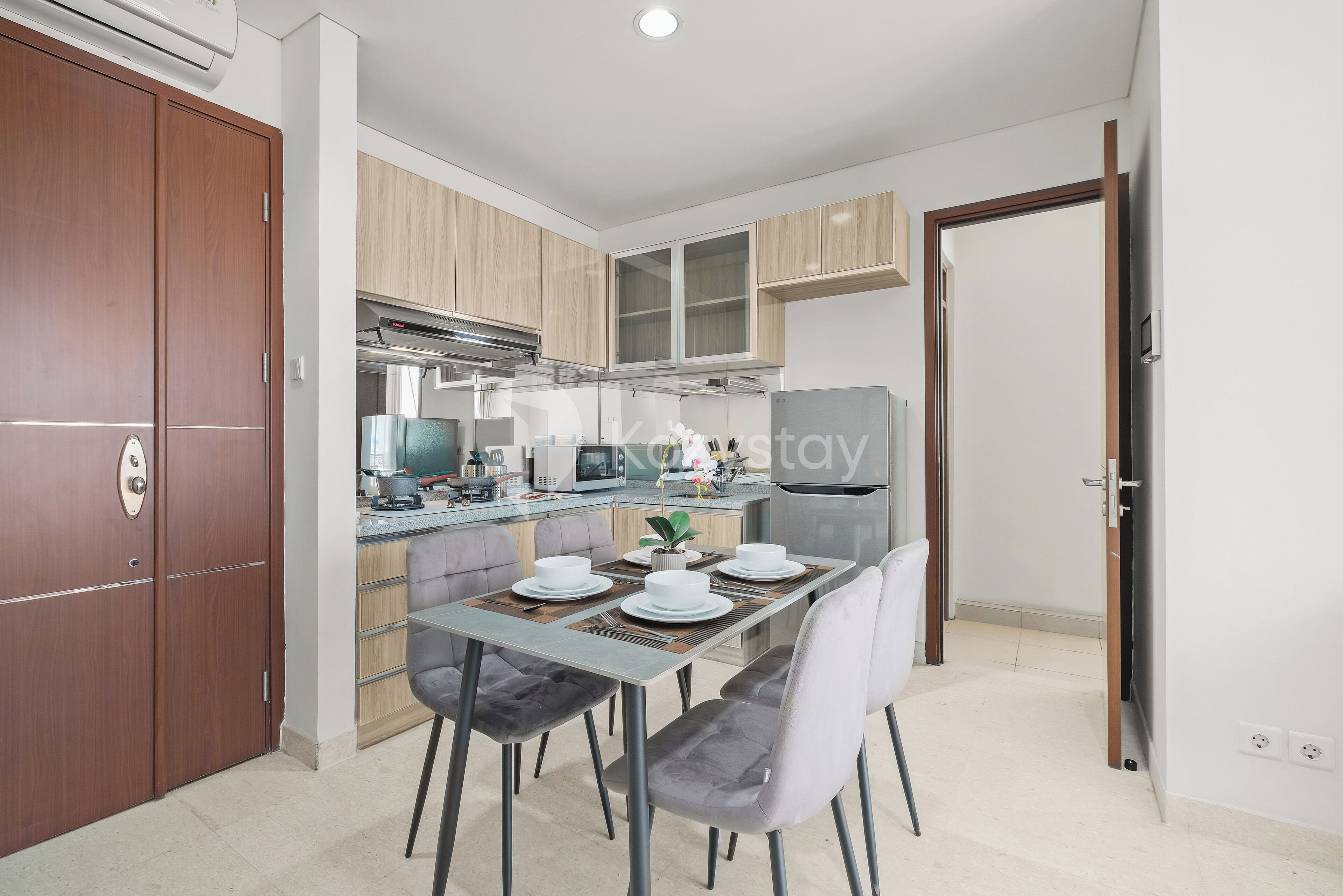 Una cocina moderna con armarios de madera, una mesa de comedor con cuatro sillas y un horno empotrado.