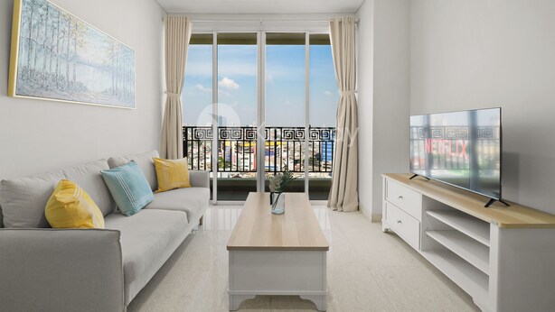 A modern living room with a sofa, coffee table, TV, and a large window with curtains. - Maruva by Kozystay - Taman Sari (Jakarta)