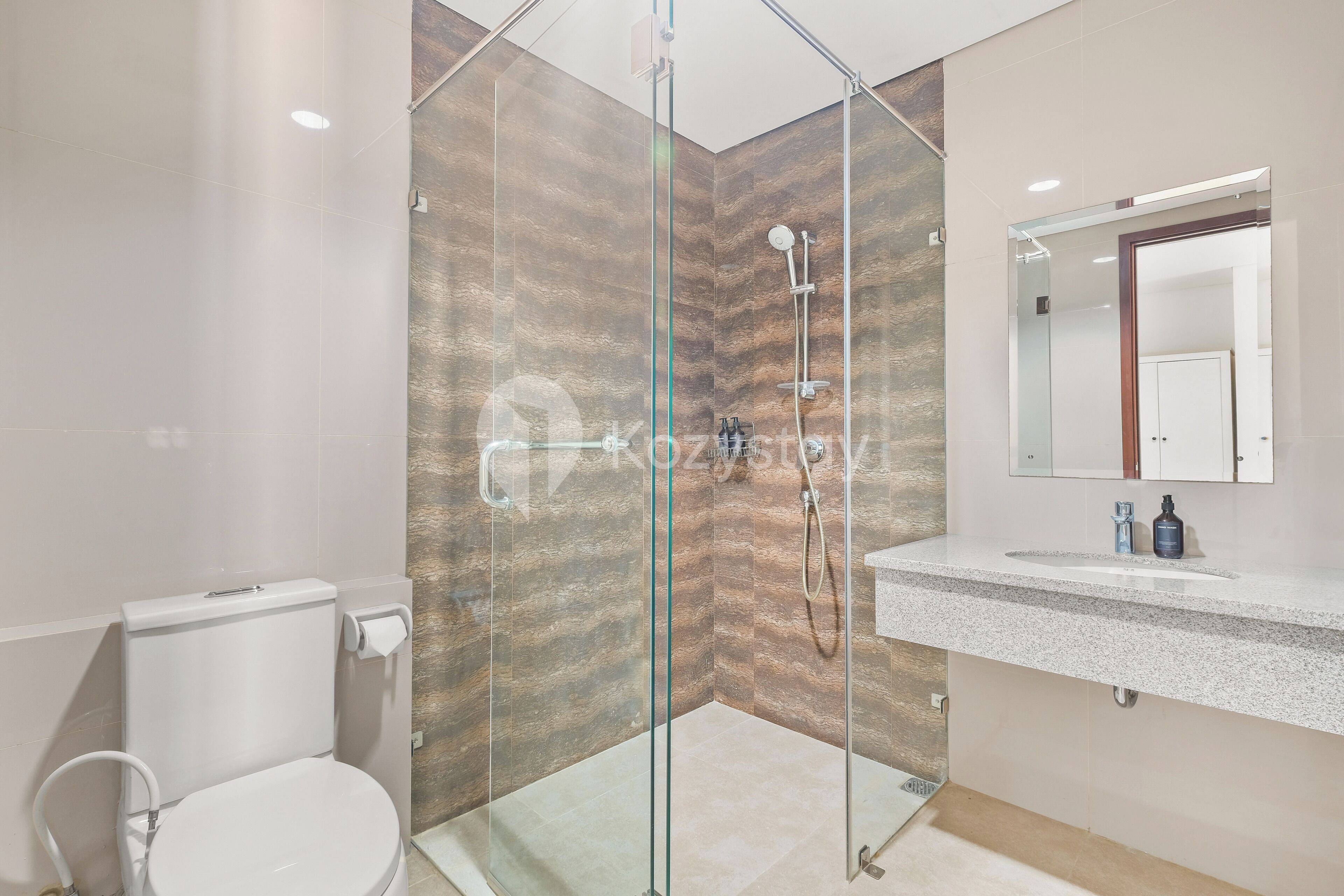 A modern bathroom with a glass-enclosed shower, a toilet, and a sink with a mirror above it.