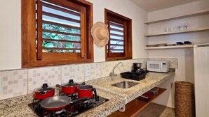 Cocina con encimeras de granito, un lavamanos, microondas y estufa con ollas.