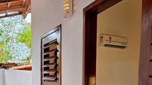 Una habitación con cama, aire acondicionado de pared y ventana con persianas.
