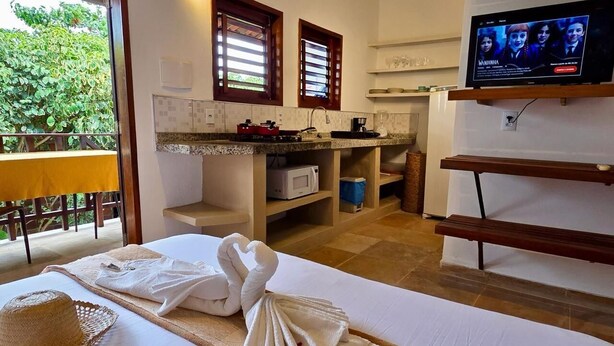 Habitación de hotel con cama, televisión, kitchenette y balcón con vistas a zonas verdes.