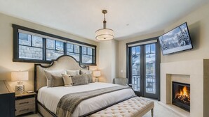 A bedroom with a large bed, a fireplace, and a TV on the wall. - Tranquil Blackstone Getaway 3 Bedroom Townhouse (Park City)